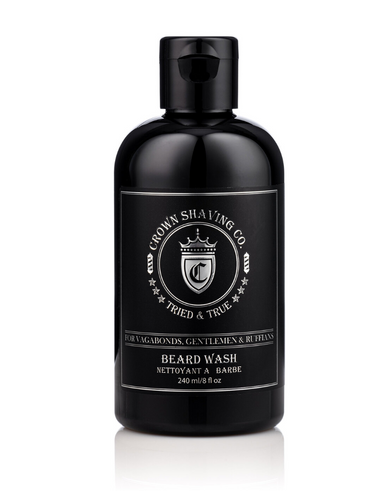 This image features a black bottle of Crown Shaving Co. Beard Wash. The label prominently displays the brand's logo and the product name